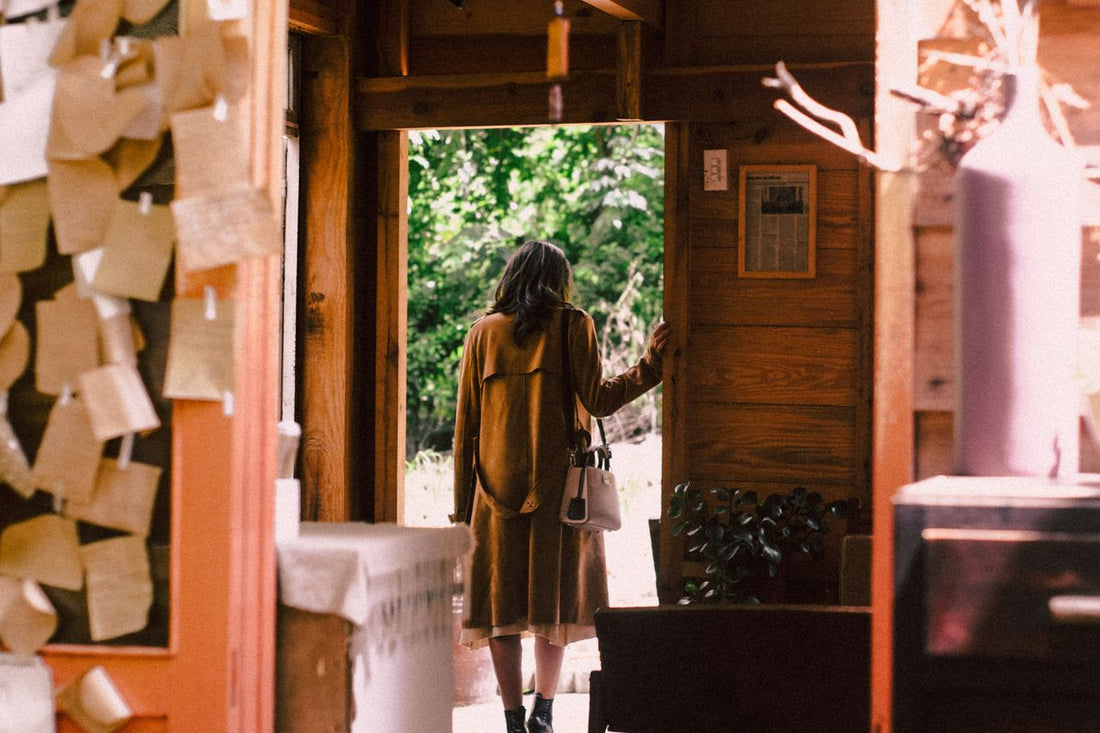 A person standing in a doorway or at the threshold between an interior and outdoor space