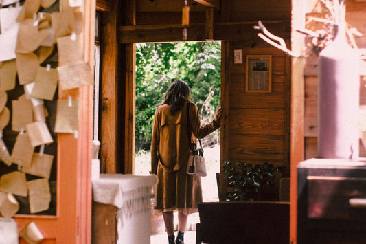 A person standing in a doorway or at the threshold between an interior and outdoor space